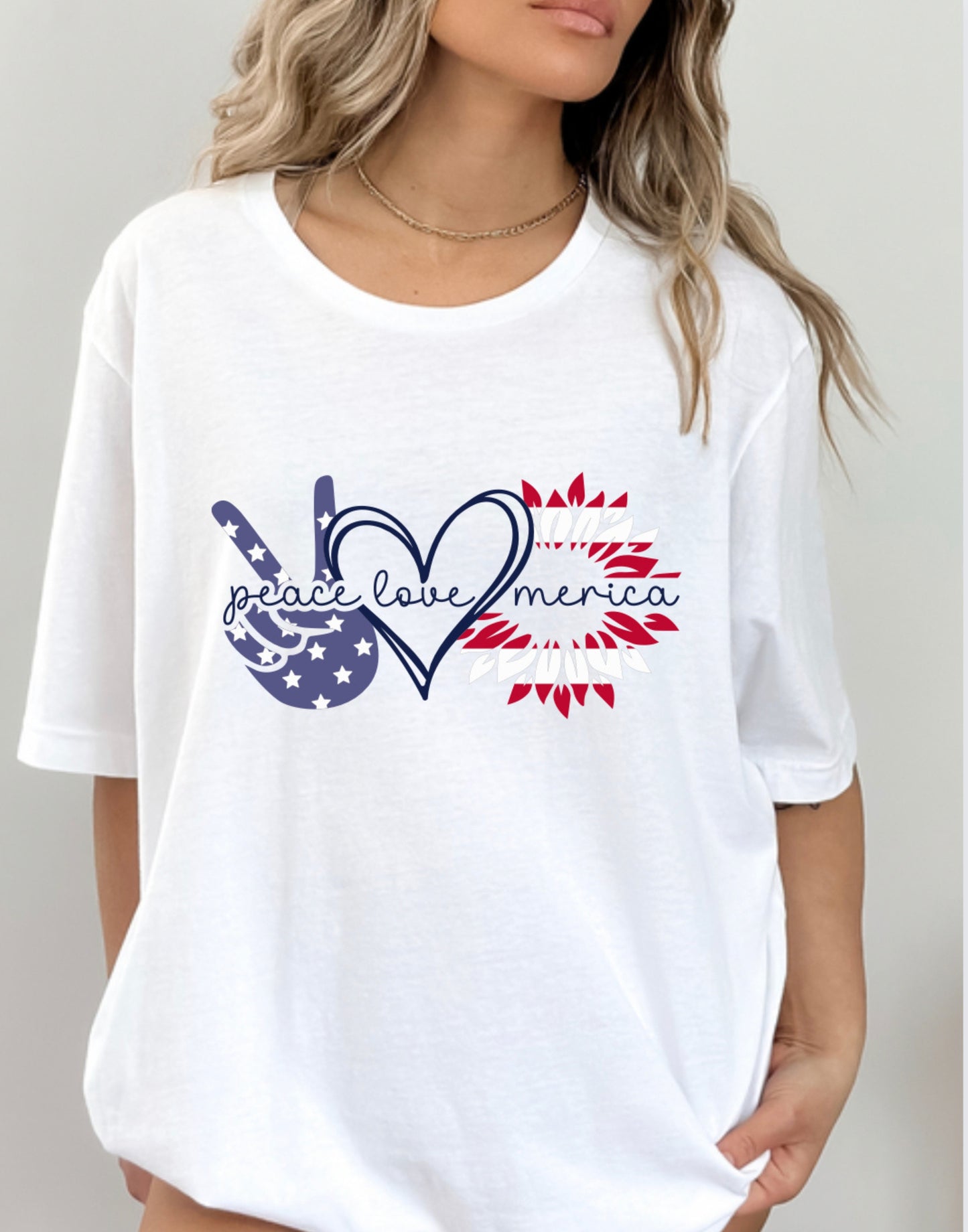 Model wearing white Bella Canvas unisex t-shirt with “Peace Love Merica” design featuring peace sign, heart, and sunflower graphic in red, white, and blue – Oaklieten woman-owned brand