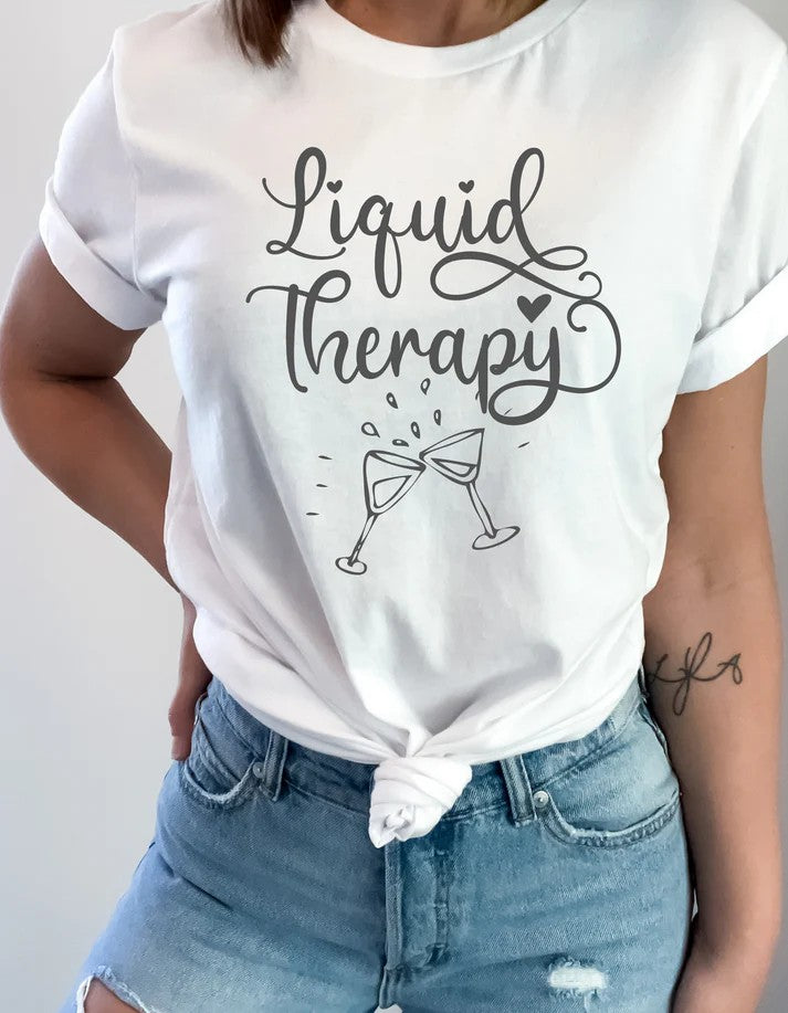 Model wearing white Gildan Softstyle unisex t-shirt with “Liquid Therapy” text and clinking wine glasses graphic – Oaklieten woman-owned brand