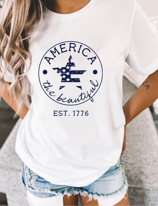 White Bella Canvas t-shirt with navy blue “America the Beautiful EST. 1776” star graphic, patriotic USA pride shirt for women, perfect for 4th of July, Memorial Day, and Independence Day celebrations.