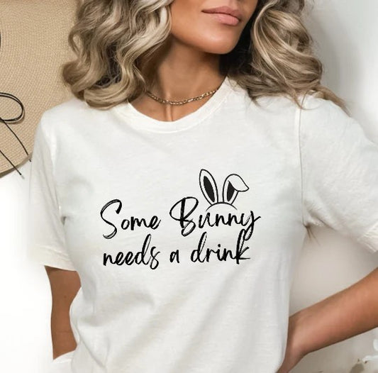 White Gildan t-shirt with playful black script that reads “Some Bunny Needs a Drink” featuring bunny ears above the word “Bunny.”